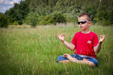 Un petit garçon médite dans un champ